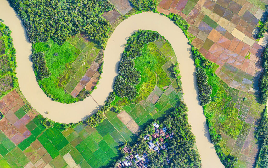 Aerial of river flowing through green fields