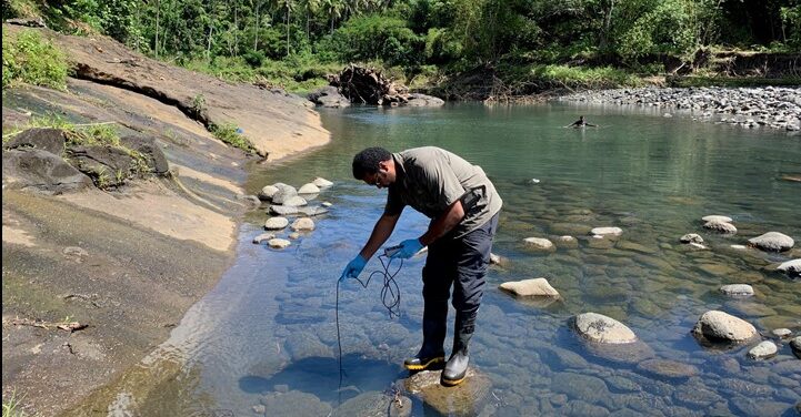 Man taking a water sample from a river.
